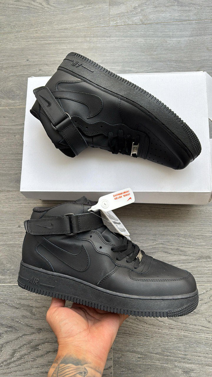 Black high-top sneakers with a visible brand tag on a gray surface