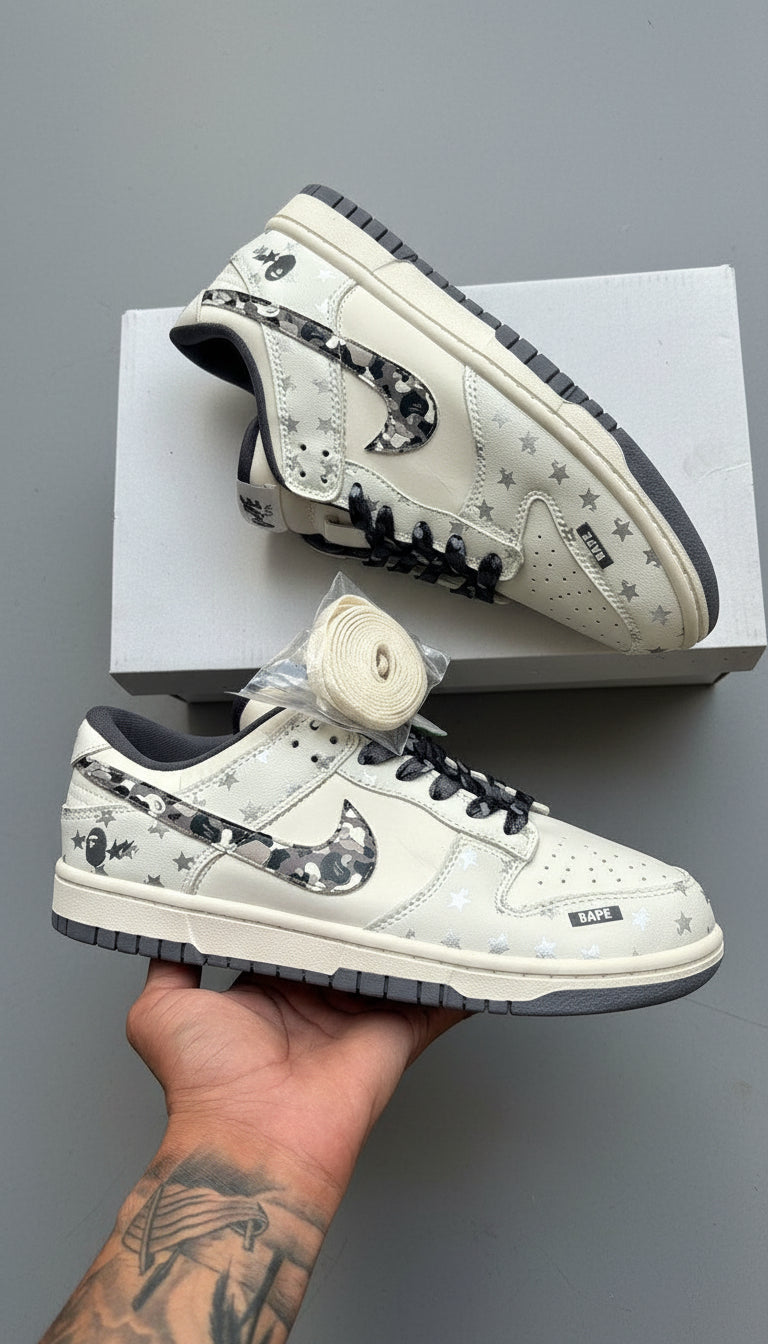 White sneakers with black and gray pattern held by a hand on a wooden surface