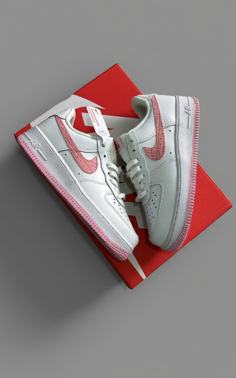White sneakers with pink accents on a red box against a gray stone background