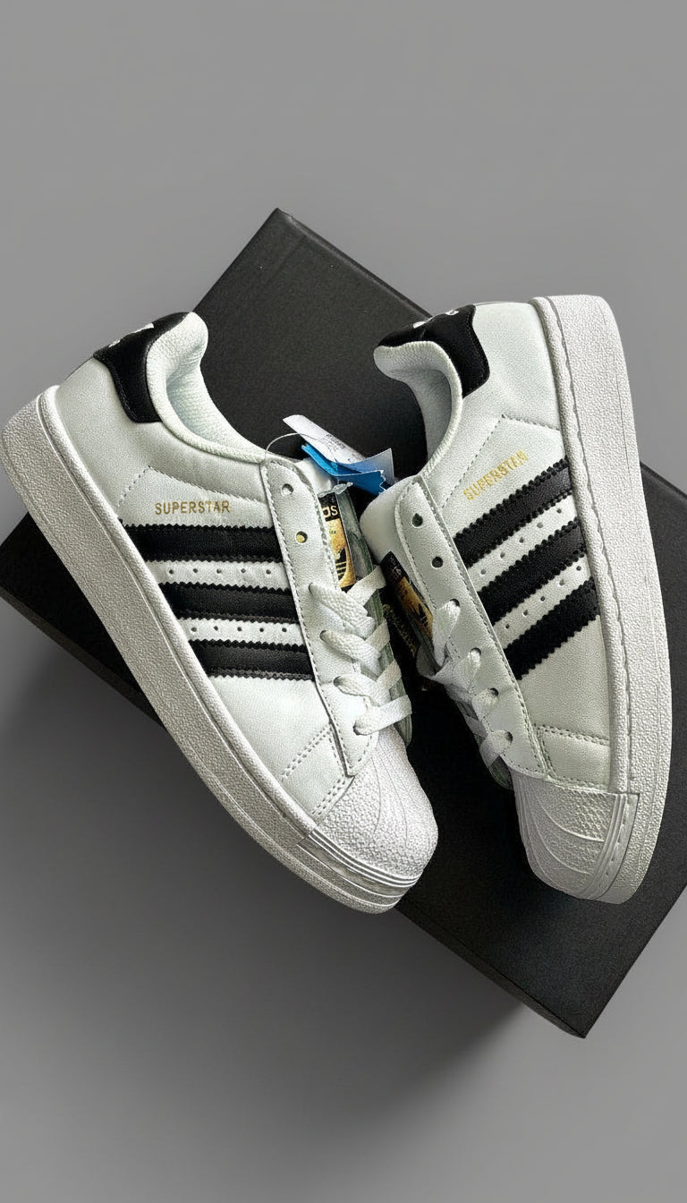 White sneakers with black stripes on a black box against a gray concrete background