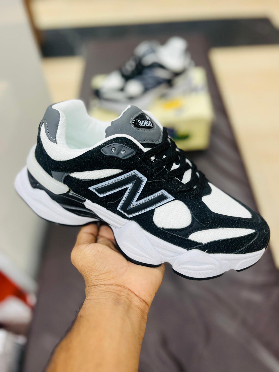 Black and white sneaker with a visible brand logo held by a hand on a blurred background