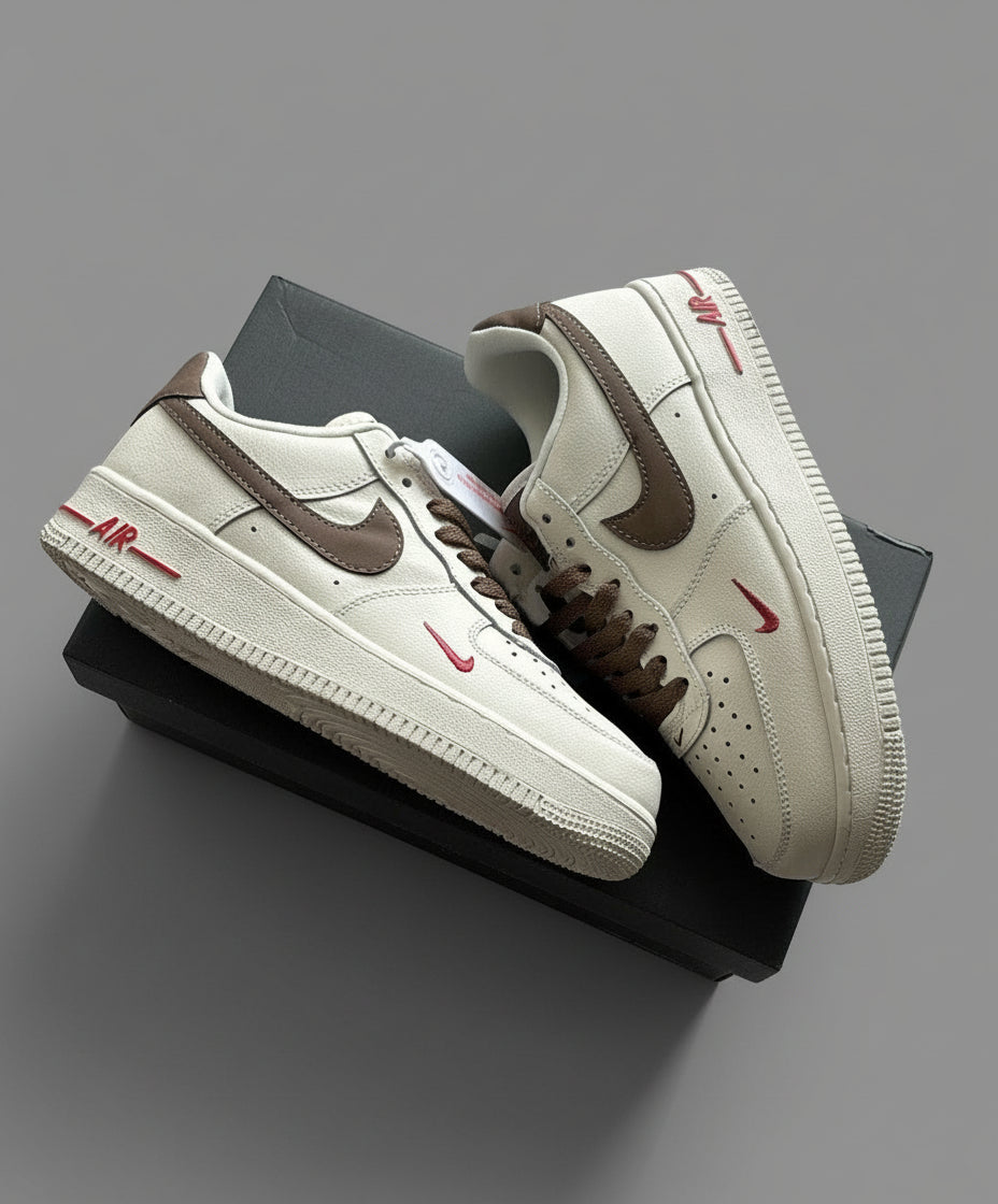 Pair of white sneakers with brown accents on a gray surface