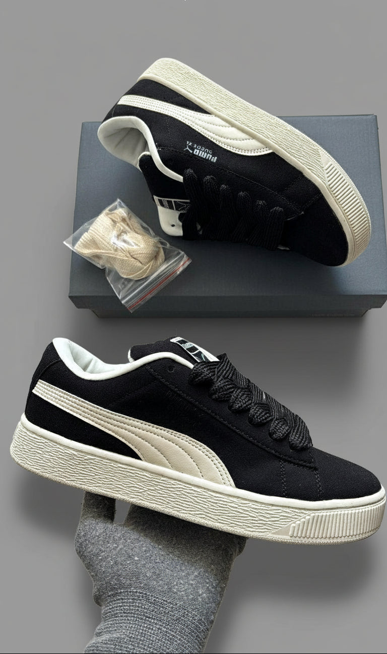 Black and white sneakers with a visible brand logo on a gray surface