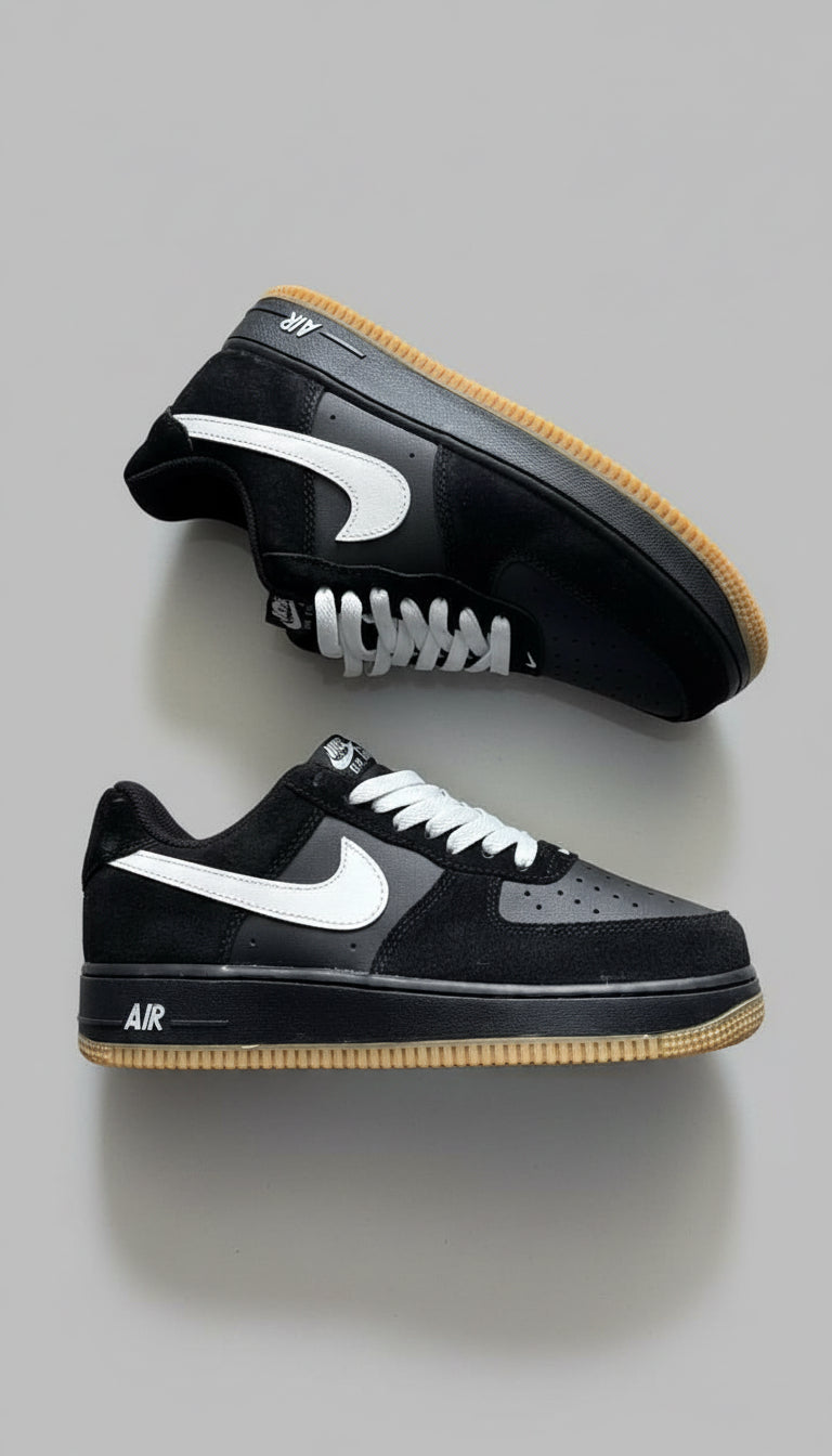 Black Nike sneakers with white swoosh logo on a gray concrete floor.