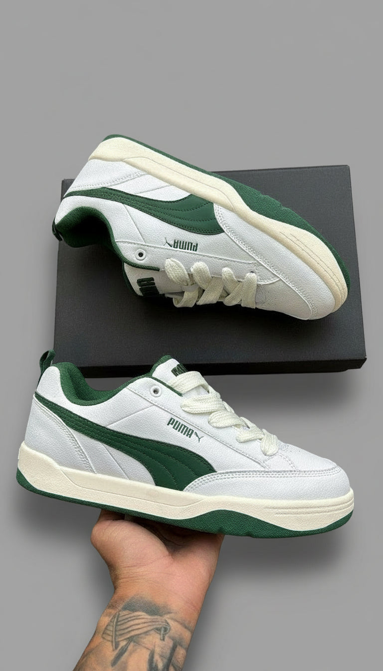 White and green sneakers with a Puma logo on a wooden floor.
