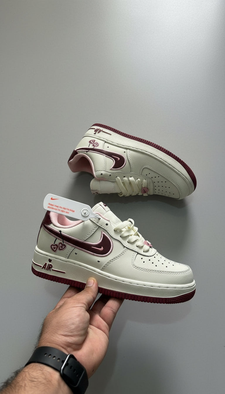 White sneakers with red accents held by a hand on a gray concrete floor.