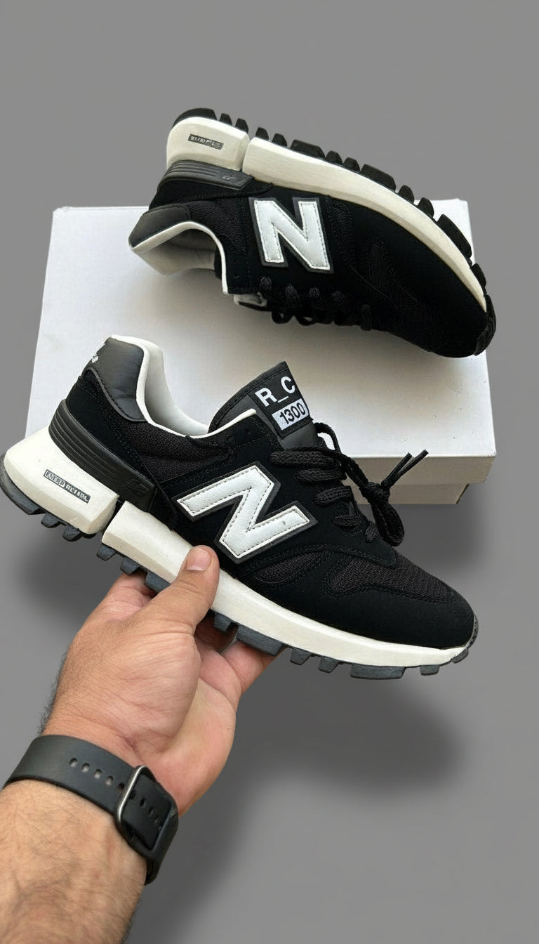 Black New Balance sneakers with white soles on a gray surface