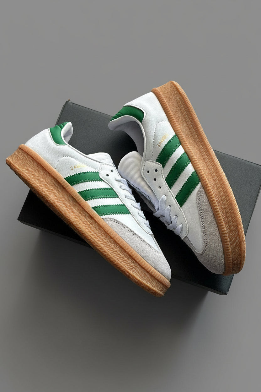 White sneakers with green stripes and brown soles on a gray surface