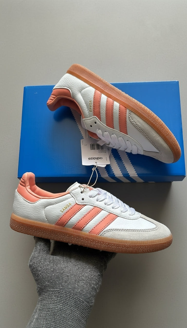 White and orange Adidas shoes with a blue box on a light gray surface