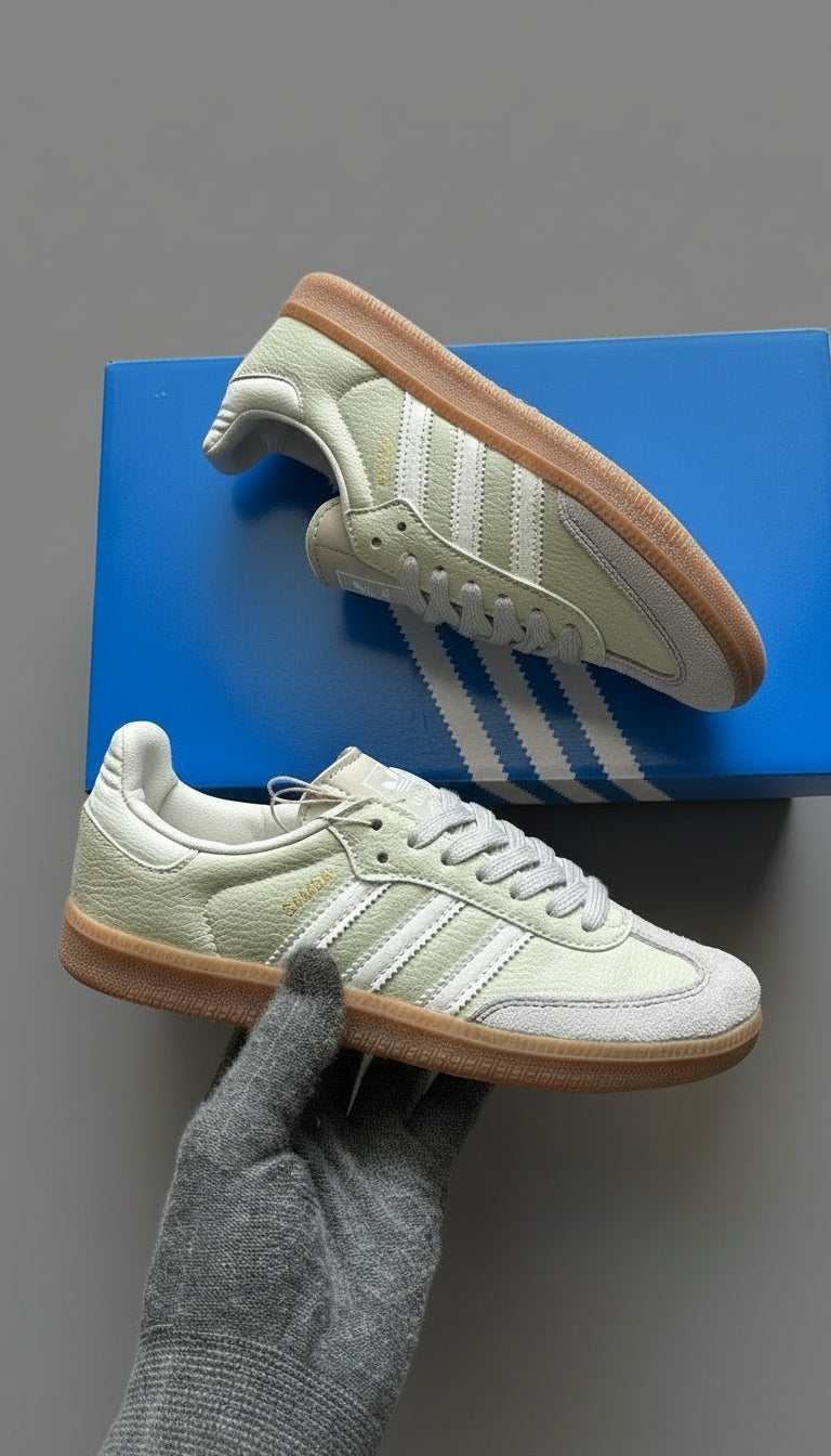 White Adidas sneakers with brown soles on a blue box against a gray background